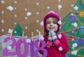 New Year 2018 concept. Beautiful small girl decorating the New Year numeral. background of a painted Christmas tree and