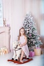 New Year 2020! The concept of Christmas, holidays and childhood. little girl rides a toy rocking horse against the background of a