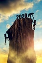 New Year 2020 concept. Hikers climbing on rock.