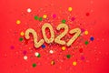 New Year concept. Shiny golden numbers 2021 and colorful confetti on a red paper background. Gift, surprise, holiday. New year Royalty Free Stock Photo