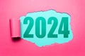 New year 2024 concept. Text of 2024 on green background in hole of torn pink paper