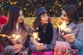 New Year concept. Women friends burning sparklers in Lviv by Christmas tree. Girls holding shopping bags and gifts Royalty Free Stock Photo