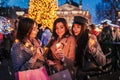 New Year concept. Women friends burning sparklers in Lviv by Christmas tree on street fair. Girls holding shopping bags Royalty Free Stock Photo