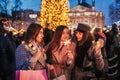 New Year concept. Women friends burning sparklers in Lviv by Christmas tree on street fair. Girls holding shopping bags Royalty Free Stock Photo