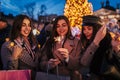 New Year concept. Women friends burning sparklers in Lviv by Christmas tree on street fair. Girls holding shopping bags Royalty Free Stock Photo
