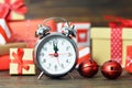 New Year countdown. Midnight clock and gift boxes on wooden background