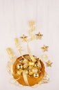 New Year decor, gold bowl with christmas stars, balls, ribbons on white wood board, top view, vertical. Royalty Free Stock Photo