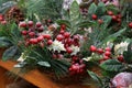 New year decor from red berries and green leaves of coniferous branches under artificial snow in a basket on the table Royalty Free Stock Photo