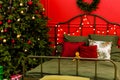 New Year decorated bedroom. Spacious red bedroom with decorated Christmas tree and Christmas wreath on wall. Xmas in the evening