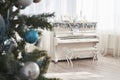 New Year decoration. Christmas tree near white piano at the window background Royalty Free Stock Photo