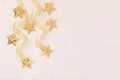 New Year decorations, gold stars and curl ribbon on soft white wooden background. Royalty Free Stock Photo