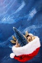 Red hat of Santa Claus and decorative tree and cones on deep blue murmur background