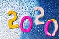 2020 New year design concept. Colored figures of plasticine on a blue background with water drops Royalty Free Stock Photo