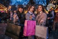 New Year concept. Women friends burning sparklers in Lviv by Christmas tree on street fair. Girls holding shopping bags Royalty Free Stock Photo