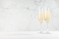 New Year festive background with bright fizz champagne in two glasses in white modern elegant interior on wood table, copy space.