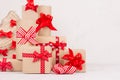 New Year festive background - kraft gift boxes with red bows and ribbons and christmas tree closeup on white wood board. Royalty Free Stock Photo