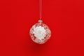 New Year glass ball transparent with white lace snowflake on red paper background