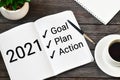 2021 New Year. Goal,plan, action text on notepad with office accessories on a wooden background Royalty Free Stock Photo