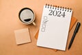 New year goals 2024 concept. Notebook, coffee cup and pen on brown background Royalty Free Stock Photo