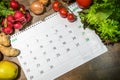 New year goals, eating healthy and lose weight, January month calendar surrounded by vegetables and fruits on a wooden table, top