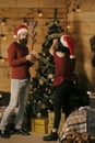 New year guy and girl decorate Christmas tree. Royalty Free Stock Photo