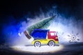 Miniature car with fir tree on Snowy Winter Fores, or toy car carrying a christmas tree and at night time Royalty Free Stock Photo