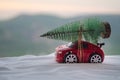 New Year holiday concept. Miniature car with fir tree on Snowy Winter Forest, or toy car carrying a Christmas tree and at snowy ro Royalty Free Stock Photo
