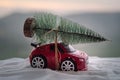 New Year holiday concept. Miniature car with fir tree on Snowy Winter Forest, or toy car carrying a Christmas tree and at snowy ro Royalty Free Stock Photo