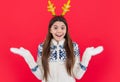 new year holiday. surprised teen girl in new year sweater and deer antlers in studio. Royalty Free Stock Photo