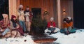 New Year holiday vacation. Group of happy friends drink tea talking at cozy Christmas tree house terrace slow motion. Royalty Free Stock Photo