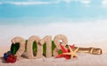 New Year inscription 2018, bottle of champagne, gifts and starfish in the sand on beach.