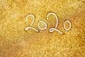 2020 New Year inscription. Golden glitter background texture. Christmas theme. New Year celebration. Confetti on the table.