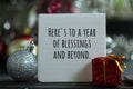 New Year inspirational quote - Here`s to a year of blessings and beyond. With red Christmas gift box and white ball ornament.