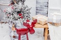 New Year installation where there is a bench with gifts, a red iron deer and a wooden barrel with Christmas tree branches