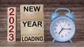 2023 New Year Loading text on wooden blocks and wooden background with clock. Goal setting and New Year resolutions. Christmas