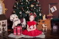 New Year 2020. Merry Christmas, happy holidays. Little girl in a red dress holds a vintage wooden nutcracker toy near a classic Ch Royalty Free Stock Photo