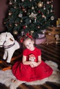 New Year 2020. Merry Christmas, happy holidays. Little girl in a red dress holds a vintage wooden nutcracker toy near a classic Ch Royalty Free Stock Photo