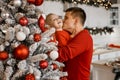 New Year mood. A loving daddy is kissing his laughing little son on the cheek near Christmas tree