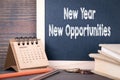 New year new opportunities. paper calendar and chalkboard on a wooden table