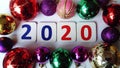 New 2020 year. The numbers 2020 are red and blue between multi-colored glass Christmas balls. Glimmers of lighting on Royalty Free Stock Photo