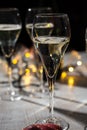 New year party, small bubbles of brut champagne cava or prosecco wine in tulip glasses with garland lights on background