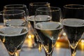 New year party, small bubbles of brut champagne cava or prosecco wine in tulip glasses with garland lights on background