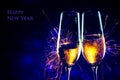 New Year party time with two champagne glasses and sparklers against a dark blue background with sample text Happy New Year Royalty Free Stock Photo