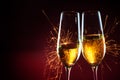 New Year party time with two champagne glasses and sparklers against a dark red background, copy space Royalty Free Stock Photo