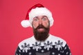 New year party. Unexpected surprise. surprised bearded man santa hat. brutal hipster favorite sweater red background Royalty Free Stock Photo