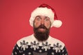 New year party. Unexpected surprise. surprised bearded man santa hat. brutal hipster favorite sweater red background Royalty Free Stock Photo