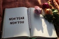 New year personal notes on a notebook with wilted roses and a pen on the table. Motivational note a book - New Year, New You. Royalty Free Stock Photo