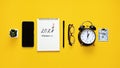 New year resolution, Goals setting for the 2023 year, text 2023 loading in open notepad and alarm clock on yellow desk Royalty Free Stock Photo