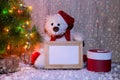 New Year`s, Christmas bear sitting under a fir tree with a wooden frame mockups for a photo or text. Royalty Free Stock Photo