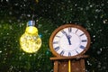 New Year`s clock and a big bright light bulb. On the dial without five twelve Royalty Free Stock Photo